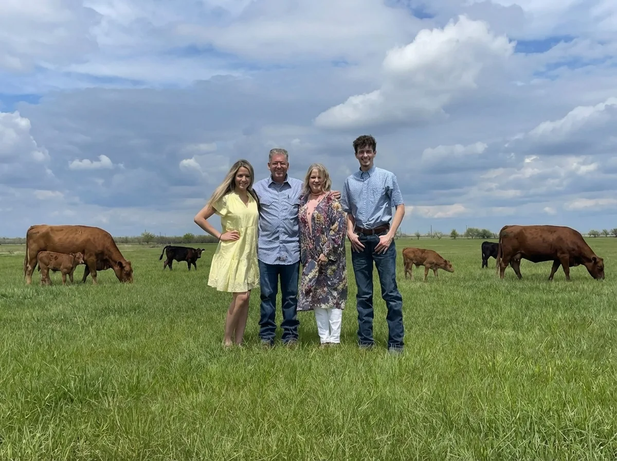 The Rankin family standing in a green pasture with their cattle grazing behind them